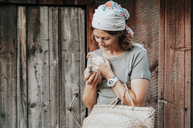 Bir kadın çiftçi, küçük sarı tavukları dikkatlice elinde tutar, onların sağlığını izler ve onları büyütür. Küçük ev çiftliği ve evcil hayvan bahçesi konsepti