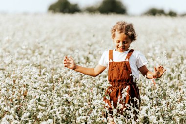 Küçük kız koşar, güneşli bir yaz gününde buğday tarlasında günün tadını çıkarır..