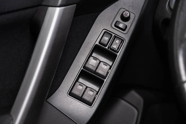 closeup of a door control panel in a new car. Arm rest with window control panel, door lock button, and mirror control