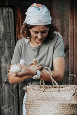 Bir bayan hostes bahçesinde yeni doğan sarı tavuklarla ilgilenir. Ev çiftçiliği