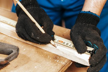 Yakından bakınca tahta bir tahta ölçer ve dilimler için gerekli noktaları kalemle işaretler.