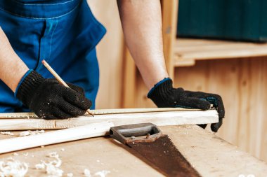 Yakından bakınca tahta bir tahta ölçer ve dilimler için gerekli noktaları kalemle işaretler.