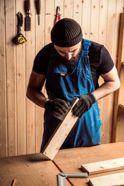 İş kıyafetleri konusunda deneyimli marangoz ve ahşap atölyesinde çalışan küçük büro sahibi atölyede çalışan çocukların helikopter bıçaklarını cilalamak için zımpara kağıdı kullanıyor.  
