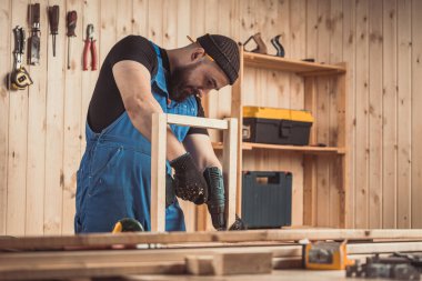 Marangoz ahşapla çalışır, adam ahşap çerçeve yapar. İnşaat ve ev yenileme, onarım ve inşaat araçları