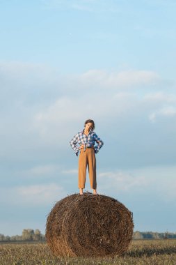 Kıvırcık saçlı bir kadının, samanlıkta gün batımına karşı duran bir çocuk gibi romantik yürüyüşü. Kadın özgürlüğü, özgürlük ve aşk kavramı.