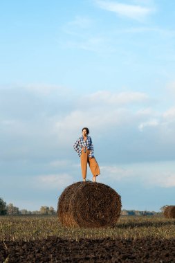 Kırsal kesimde, güneş ışığında samanlıkta genç bir kadının portresi. Samanlıkta duran güzel bir kadın. Saman yığınlarıyla yaz tarlasında dinleniyor.. 
