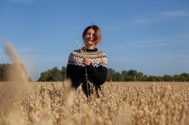 Sarı bir tarlada sarı saçlı, kıvırcık saçlı genç bir kadının romantik portresi. Arka planda bir orman. Yaratıcı Portre Kadını doğada. Tasarım sanatı konsepti.