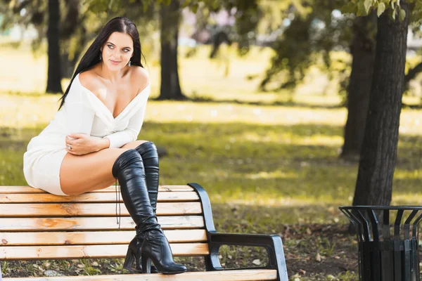 Parktaki bankta oturan bekar sarışın kadın başka tarafa bakıyor. 