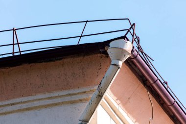 Su borusu olan eski bir evin köşesinde. Metal boru suyu emiyor. Taş duvarın arka planında fırtına suyu akışı için çelik boru var.