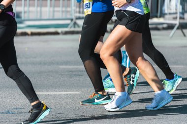 Novosibirsk, Rusya - 12 Eylül 2020: Raevich Half Marathon. Asfalttaki koşu pisti ve saha atletlerinin bacaklarına yakın çekim. Maraton koşucuları özel spor ayakkabılarla