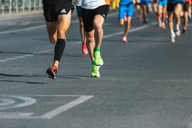 Novosibirsk, Rusya - 12 Eylül 2020: Raevich Half Marathon. Asfalttaki koşu pisti ve saha atletlerinin bacaklarına yakın çekim. Maraton koşucuları özel spor ayakkabılarla