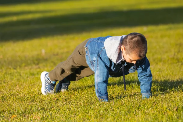 Cheerful Boy Denim Jacket Does Push Ups Lawn City Park — Stock Photo, Image