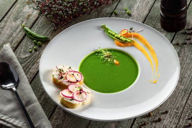 Kremalı bezelye çorbası bir RIM çorba plaka. Rustik ahşap bir masa üzerinde klasik Avrupa gıda.