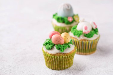 Parlak arka planda mastik yumurta ve çim ile şenlikli cupcakes. Paskalya tatili konsepti. Boşluk Kopyala