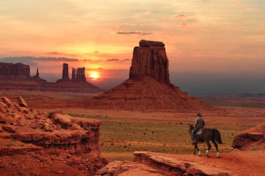 Bir kovboy atlı batımında Anıt Vadisi kabile Parkı içinde Utah-Arizona sınırındaki, ABD
