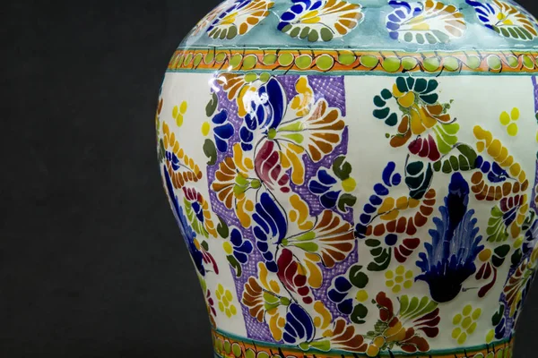 A talavera vase with a black background with a medium close up to start flirting with you