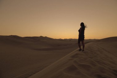 Kadın kumul üzerinde rahatlatıcı, Huacachina, Ica, Peru.The sunset çöl görünümü vaha kasabası hayran.