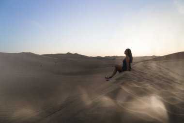 Kadın kumul üzerinde rahatlatıcı, Huacachina, Ica, Peru.The sunset çöl görünümü vaha kasabası hayran.