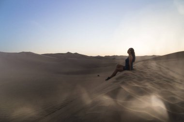 Kadın kumul üzerinde rahatlatıcı, Huacachina, Ica, Peru.The sunset çöl görünümü vaha kasabası hayran.