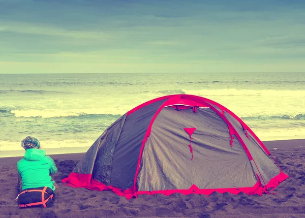 The tourist with a tent near the ocean. Travel concept.