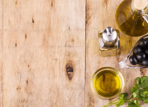 Olive Oil. Bottle of Virgin Olive Oil. Olives and Healthy Olive oil bottles and cup with parsley on old wooden table. Diet. Dieting concept. Healthy eating