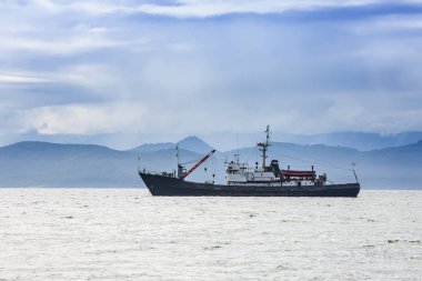Tepelerin ve volkanların arkasında büyük bir balıkçı teknesi