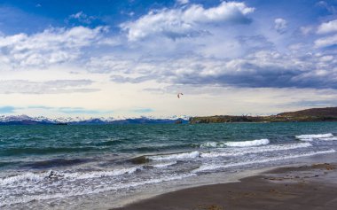 Kamçatka Yarımadası'ndaki dağlık kar bankası üzerinde dalgalar ve mavi gökyüzü ile Pasifik okyanusu