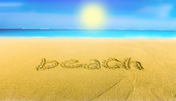 Желтый песок на пляже голубое море и надпись пляж — стоковое фото