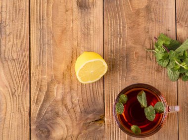 Kahverengi ahşap masada nane ve limon ile çay fincan