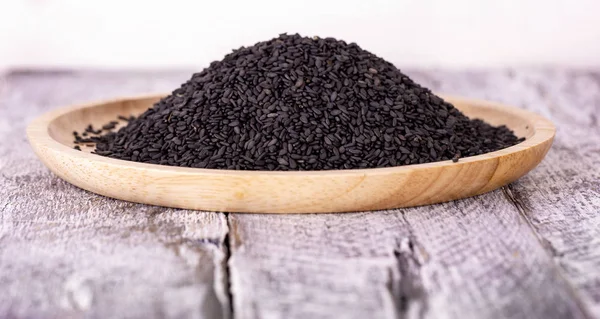 Крупним планом чорне насіння кунжуту на дерев'яній тарілці — стокове фото