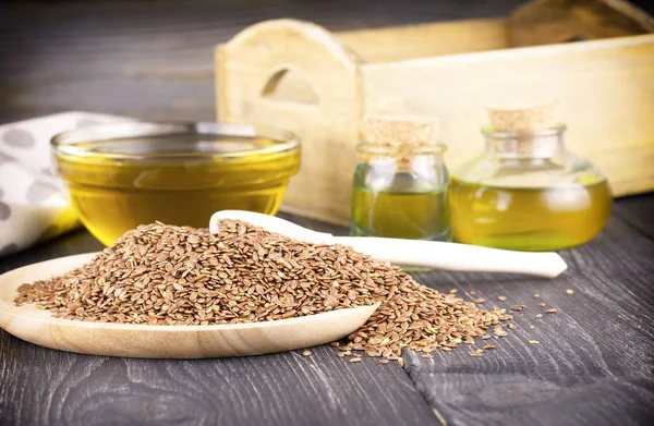 Кунжутное масло в стекле и семена на деревянном фоне — стоковое фото