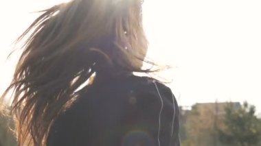 Güneş ışığı, gülümseyen genç bir kadın yaz günbatımında koşar.