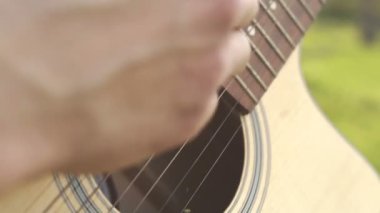 Dışarıda gitar çalan adam. Akustik gitar çalıyor. Dizeleri üzerinde el