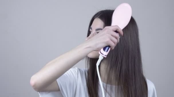 Femme avec de beaux cheveux longs et droits en utilisant un lisseur de cheveux. Brosse. — Video