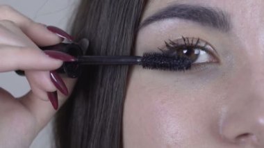 Genç ve güzel bir kadın, göz makyajı yapıyor..