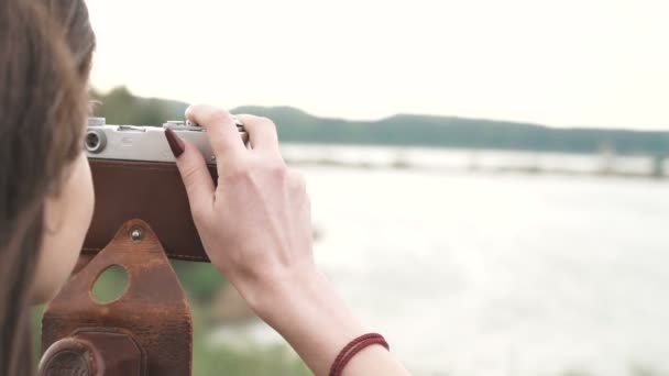 Krásná brunetka dívka dělá fotografie, oblečený v tričko natáčení se starou analogovou kamerou — Stock video