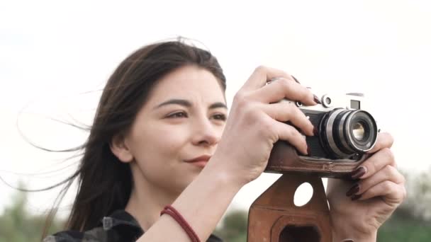 Krásná dívka dělá fotografie, na sobě tričko natáčení se starou analogovou kamerou — Stock video