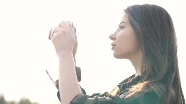 Esmer kız fotoğraf çekiyor, eski bir kamerayla tişört giyiyor.