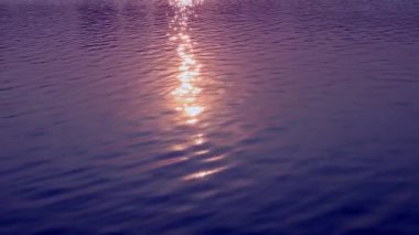 Su yüzeyi. Yansıtıcı su yüzeyine dalgalar ve dalgalarla yakından bakın. Doğal arkaplan ve gün batımı.