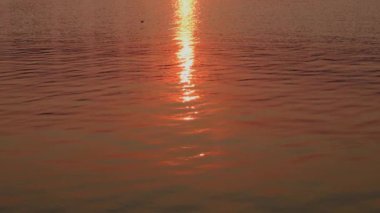 Su yüzeyi. Yansıtıcı su yüzeyine dalgalar ve dalgalarla yakından bakın. Doğal arkaplan ve gün batımı.