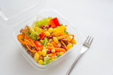 Karışımı salata açılan plastik kutu, doğal ışık beyaz zemin üzerine çatal