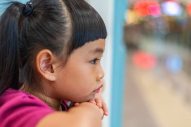 Close up the face of little girl in profile. Emotional face of thinking somthing. Chin on hands. Looking aside of image. clipart