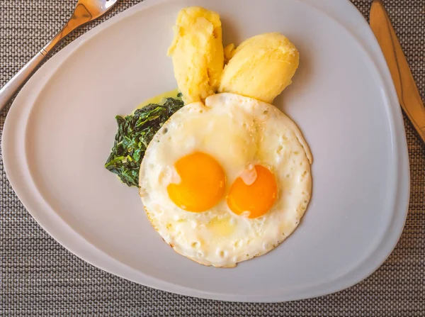 Sevimli çocuk, kahvaltıda kızarmış yumurta, patates püresi, ıspanak. Sevimli tavşan olarak gıda dekorasyon.