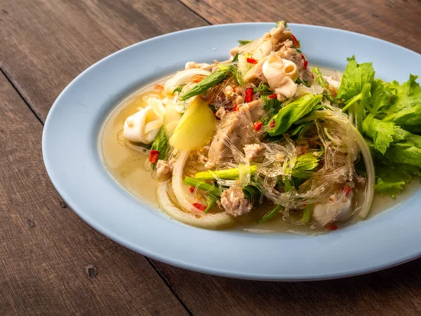 Tay gıda Yum Woon Seng denilen yakın ya da mürekkep ile ekşi ve baharatlı erişte salatası. Ahşap masa üstünde yiyecek.