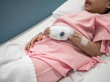 Asyalı çocuk kız hastane yatağında. Serum fizyolojik solüsyonu ile bir yandan odaklanmak.