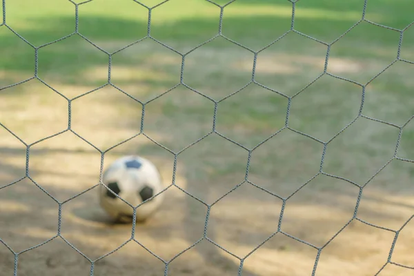 Close up football goal net, view from behind and blurred football in the front.