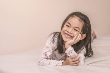 Gülümseyen kız yatakta yatıyor.