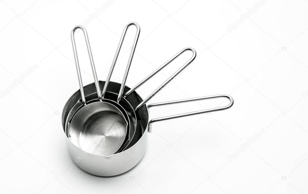 Close up measuring cups on white table, top view stainless steel measuring cup with handles stacked together.