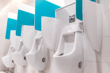 Bangkok, Tayland 'da bir mağazanın tuvaletine işerken viral enfeksiyonları önlemek için duvar uzantıları olan bir sıra pisuvar. Pisuarların düşük açılı görüntüsü. Sosyal uzaklık kavramı.