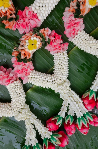 Beautiful Thai traditional garlands on banana leaf, fresh flower garland, top view vertical image.